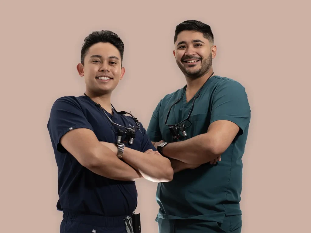 P&E Dental dentists Dr. Nathan Pinsky and Dr. Jesus Echezarreta posing together in clinical scrubs.