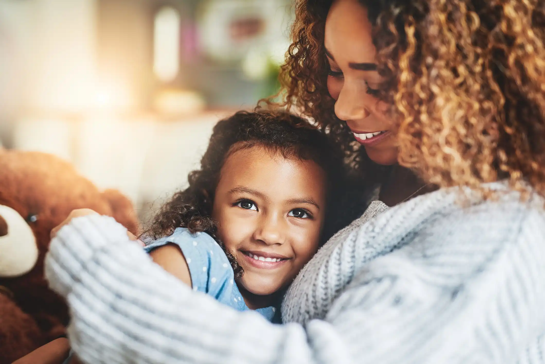 Mother and daughter smiling together while showing healthy, confident smiles