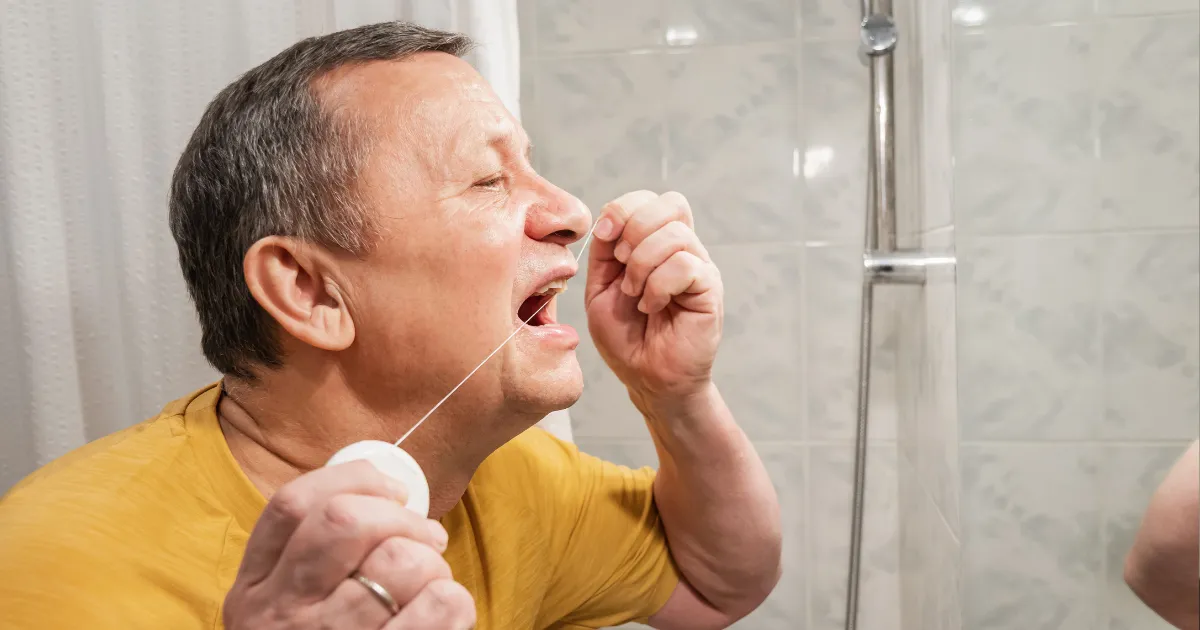 Man flossing carefully between his teeth as part of his daily oral hygiene routine