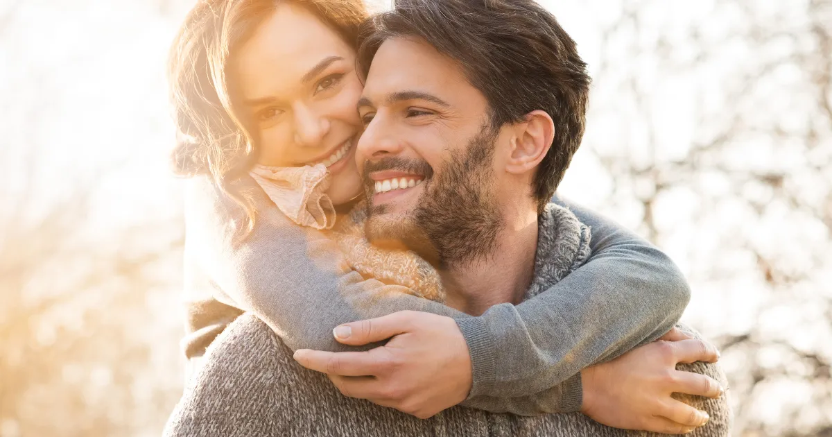 Young couple smiling and embracing while showing bright, healthy-looking teeth